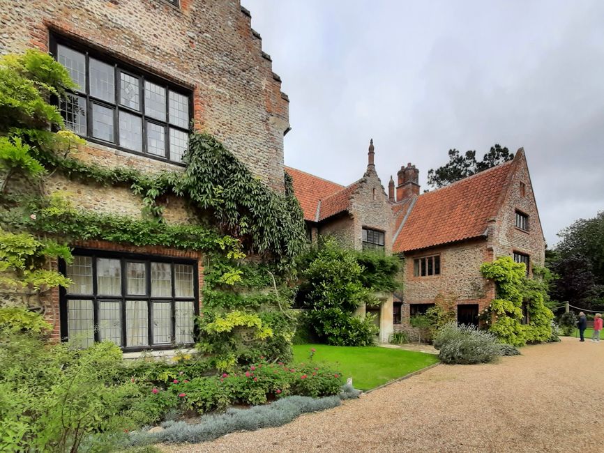 The image shows the exterior of a historic stone mansion situated on a narrow street in Manor House, Green Lanes. The building features a traditional Gothic architectural style with pointed arched win
